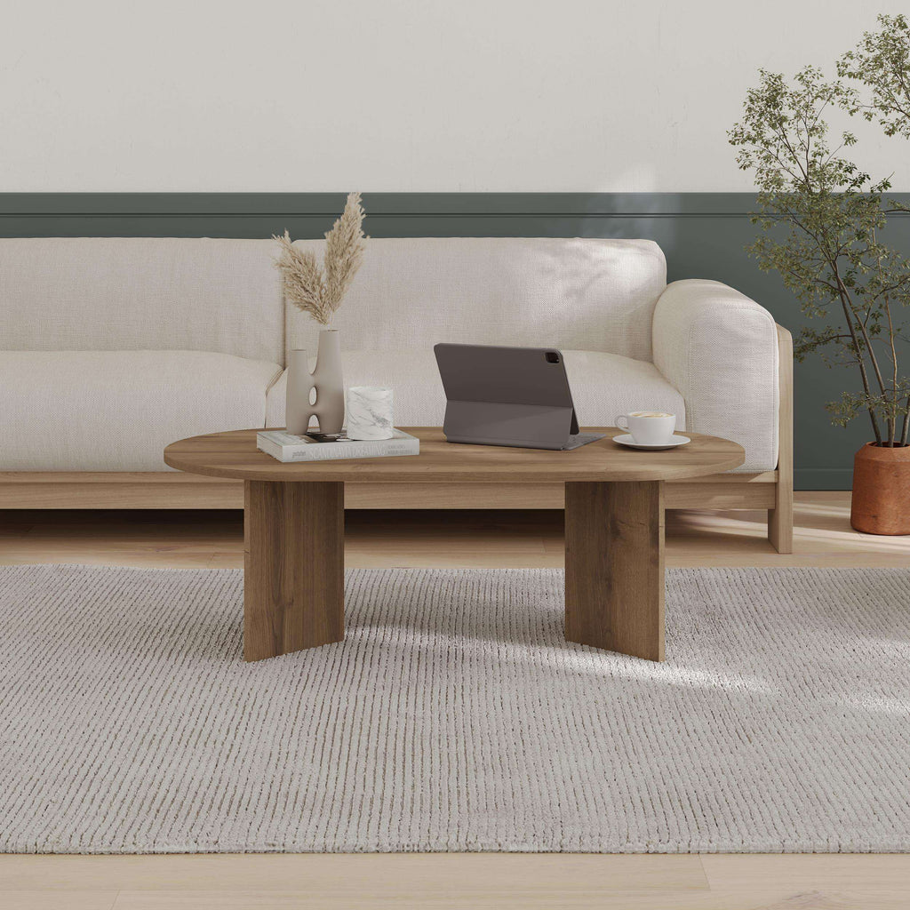 Wood oval coffee table with slender legs and rounded tabletop on a rug