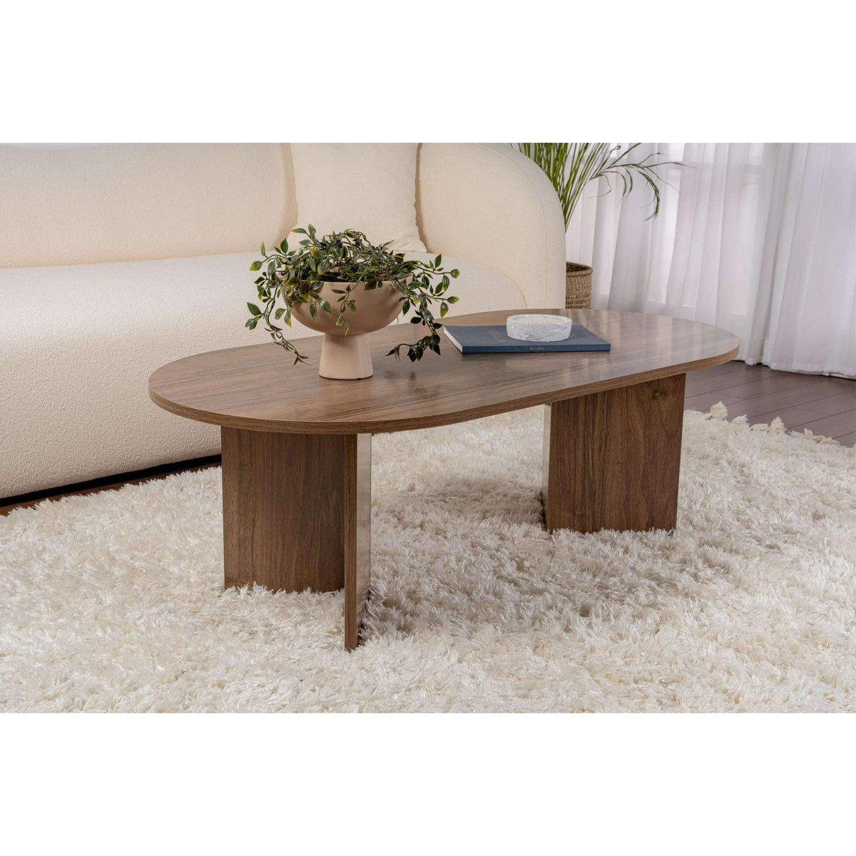 Oval walnut coffee table with tapered legs, shown on a rug in a living room