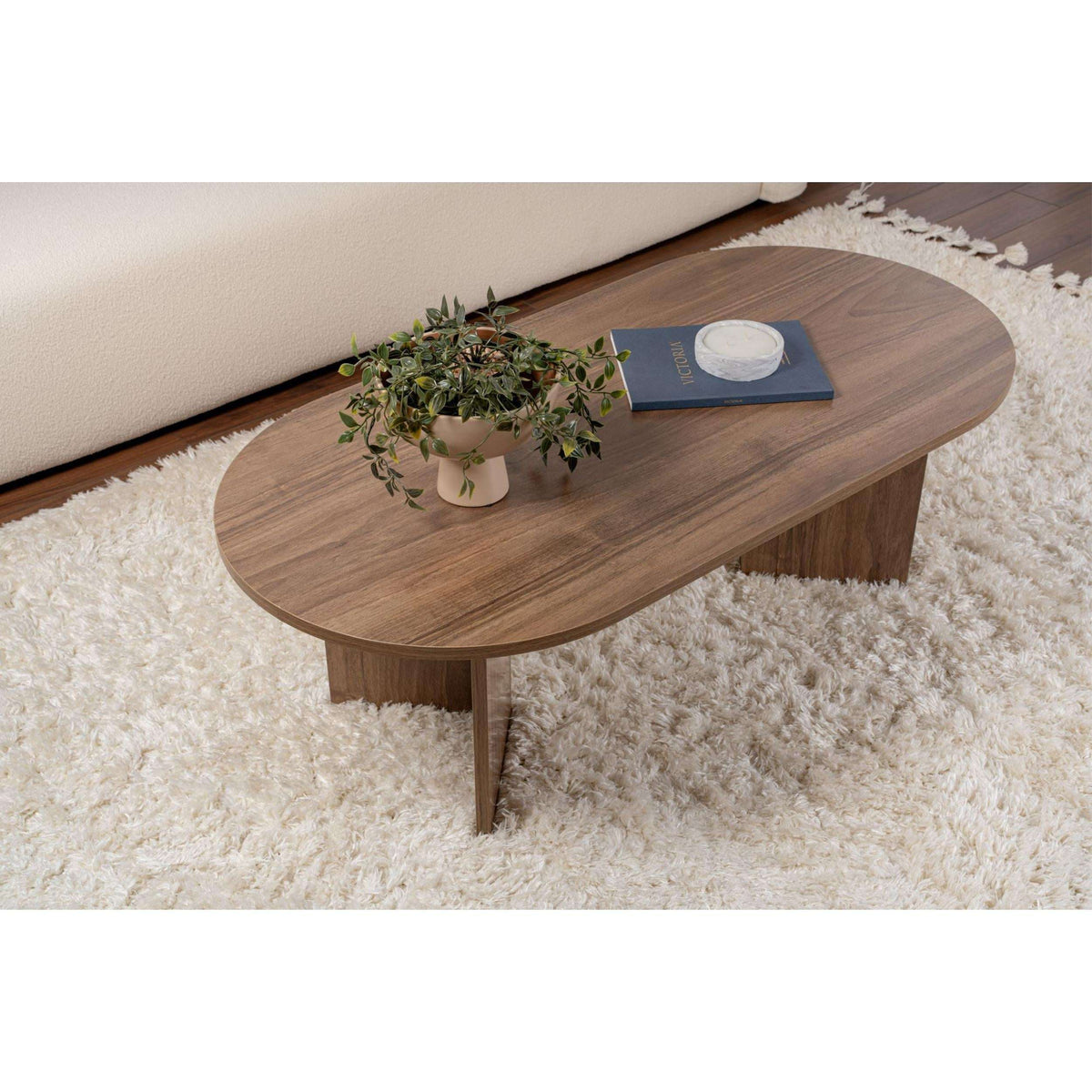 Oval walnut coffee table with rounded edge and pedestal-style legs