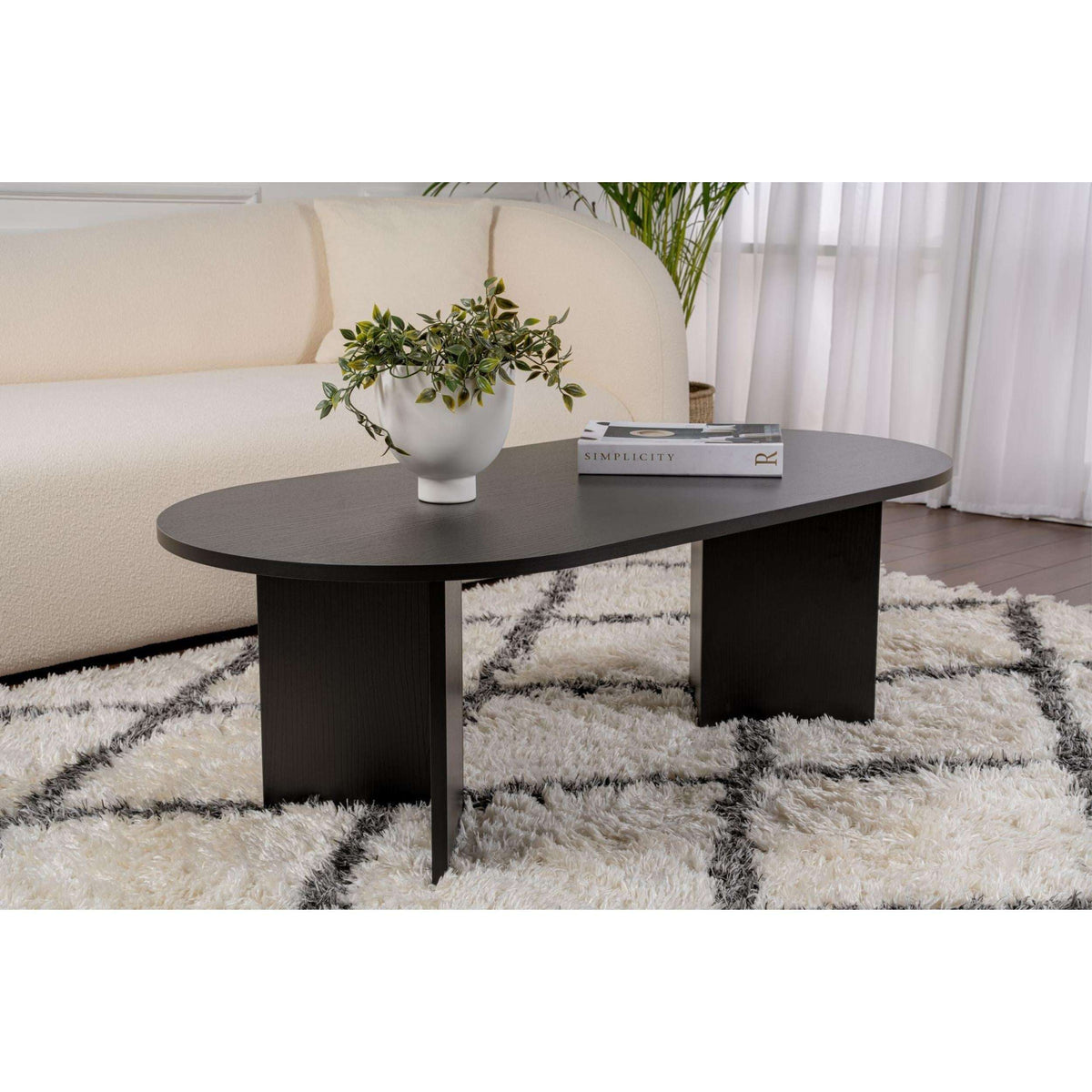 Black oval coffee table with matching legs and smooth dark top surface