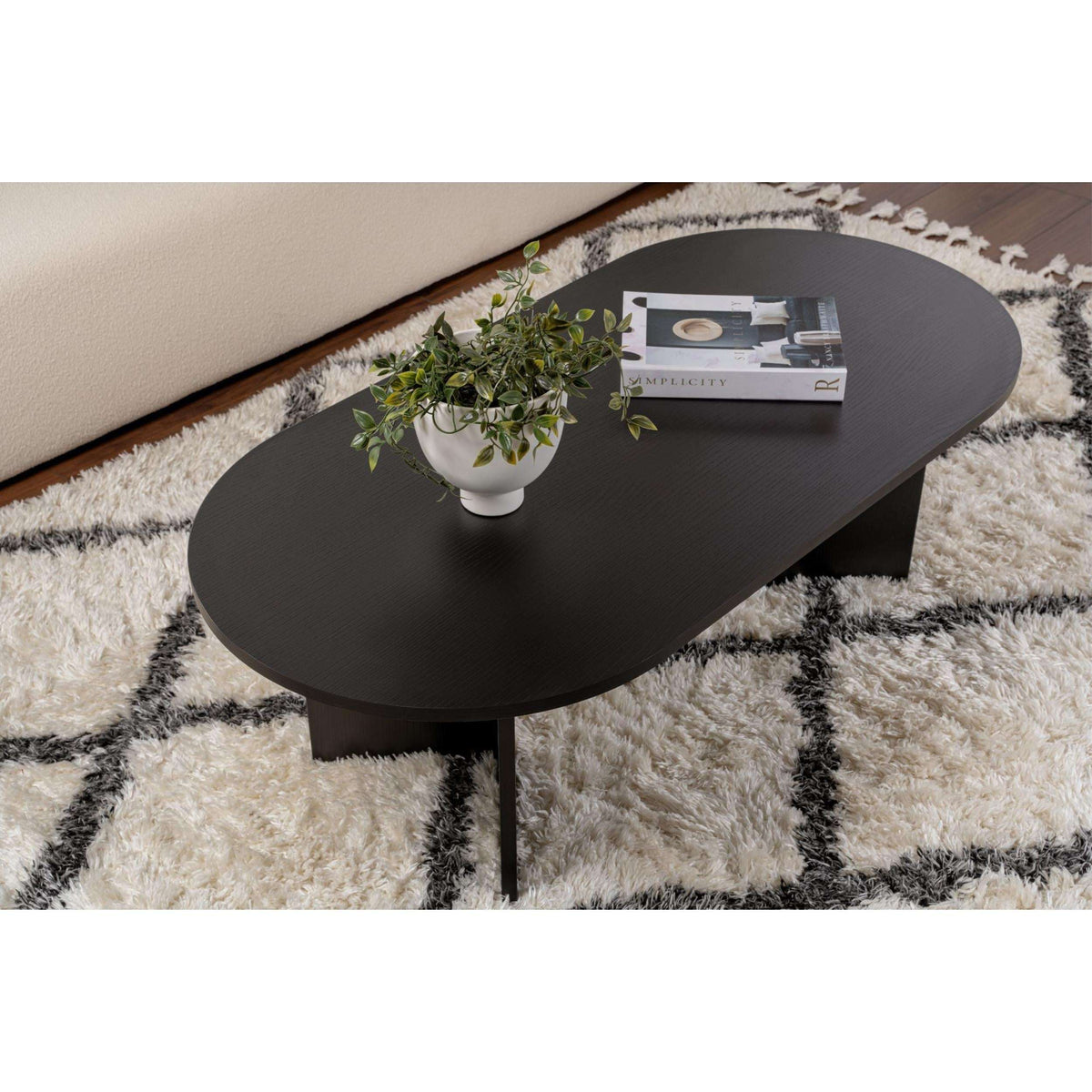 Dark oval coffee table with pedestal-like supports and rounded tabletop edge