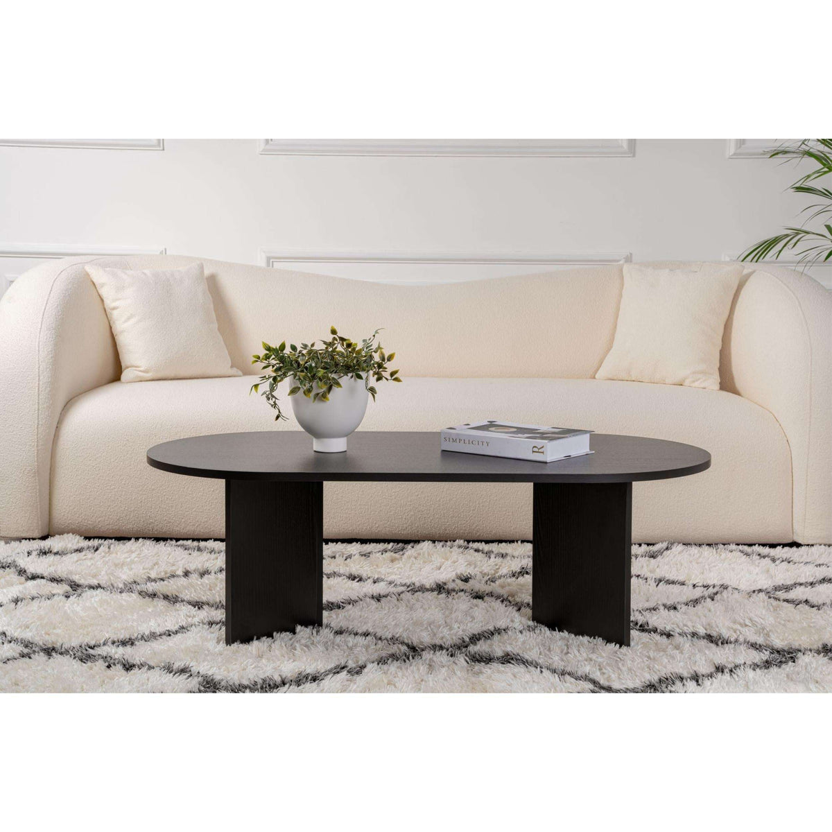 Black oval coffee table with centered legs and dark, rounded tabletop