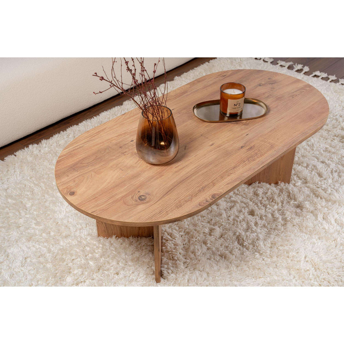 Natural wood oval coffee table with tabletop grain and four tapered supports.
