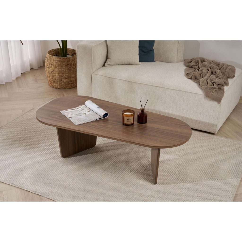 Oval coffee table in walnut-toned wood with end supports, styled with decor