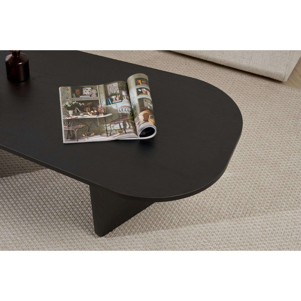 Dark oval coffee table with chamfered edges and central sculpted legs