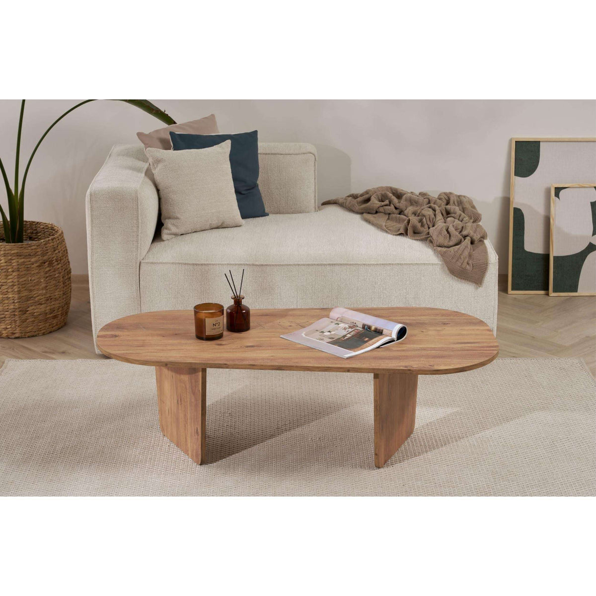 Natural wood oval coffee table with angled legs and magazine on the tabletop