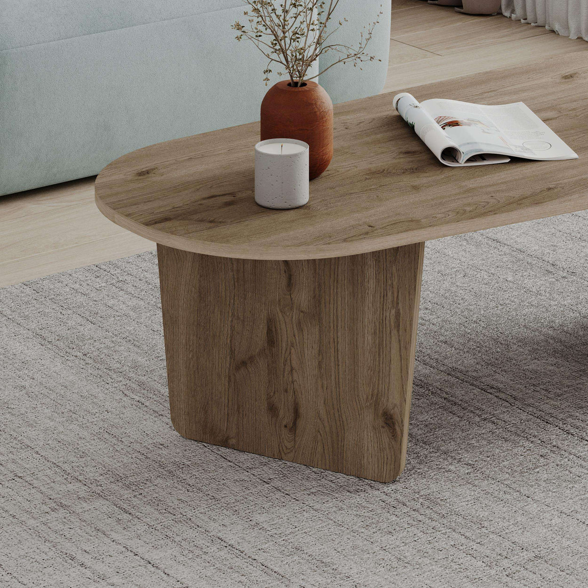 Warm brown oval coffee table with thick pedestal base and rounded tabletop