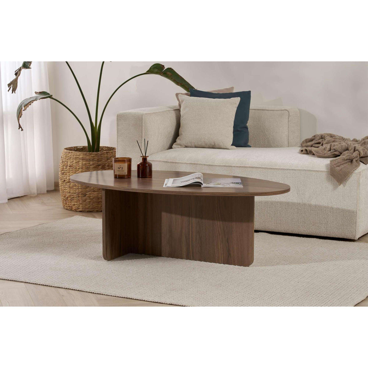 Oval dark wood coffee table with candles and an open magazine on top.