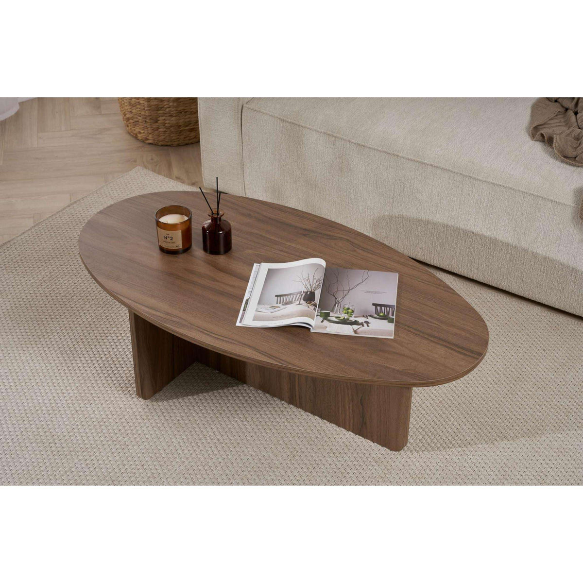 Oval dark wood coffee table with rounded edge and open magazine plus candles.
