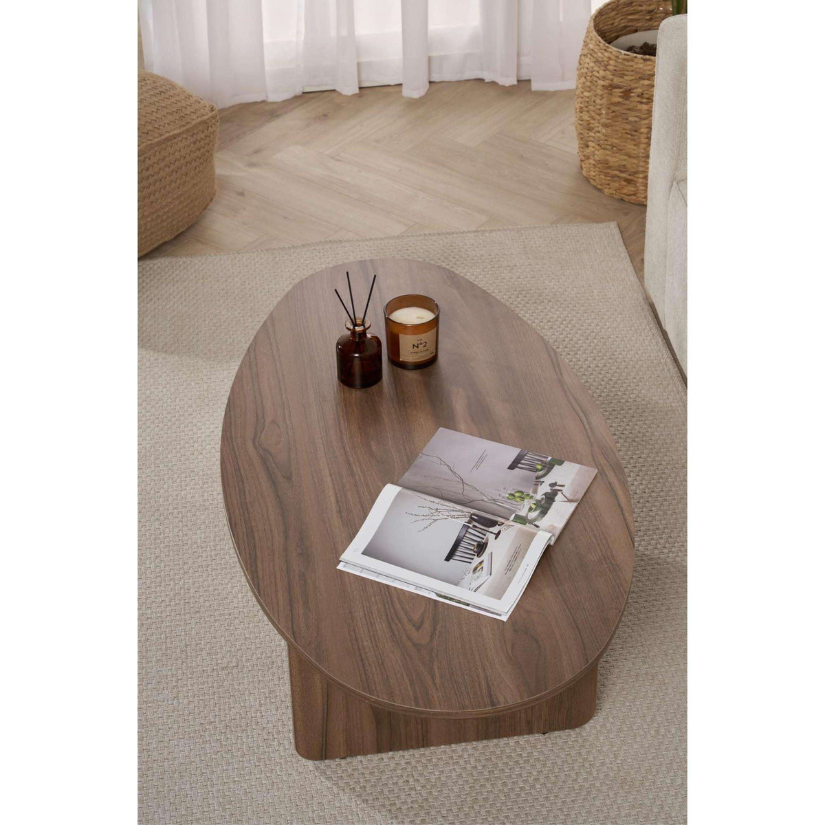 Oval dark wood coffee table with candles and an open magazine on top.