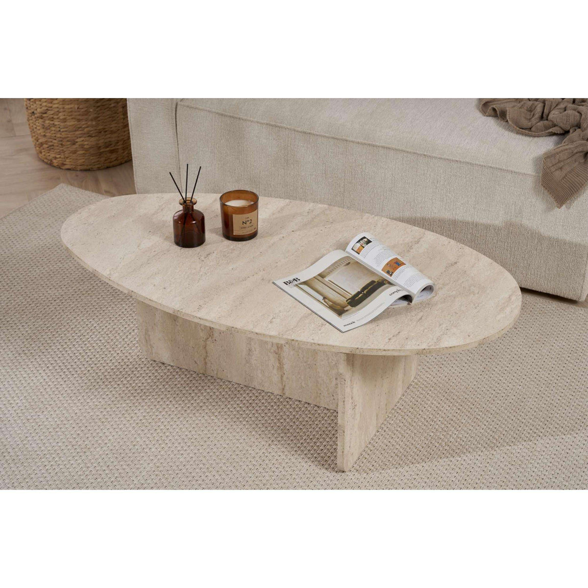 Oval coffee table with light travertine-style stone and thick block legs.