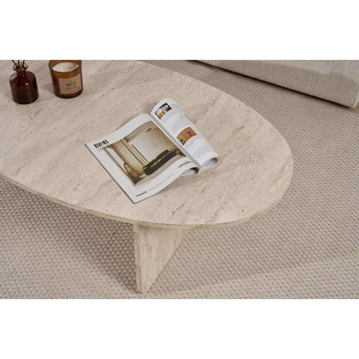 Oval light stone coffee table with tapered base and rounded tabletop edge.