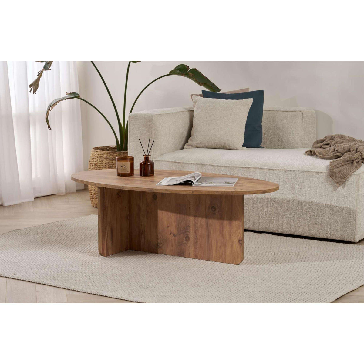 Oval dark wood coffee table with candles and a magazine on the tabletop.