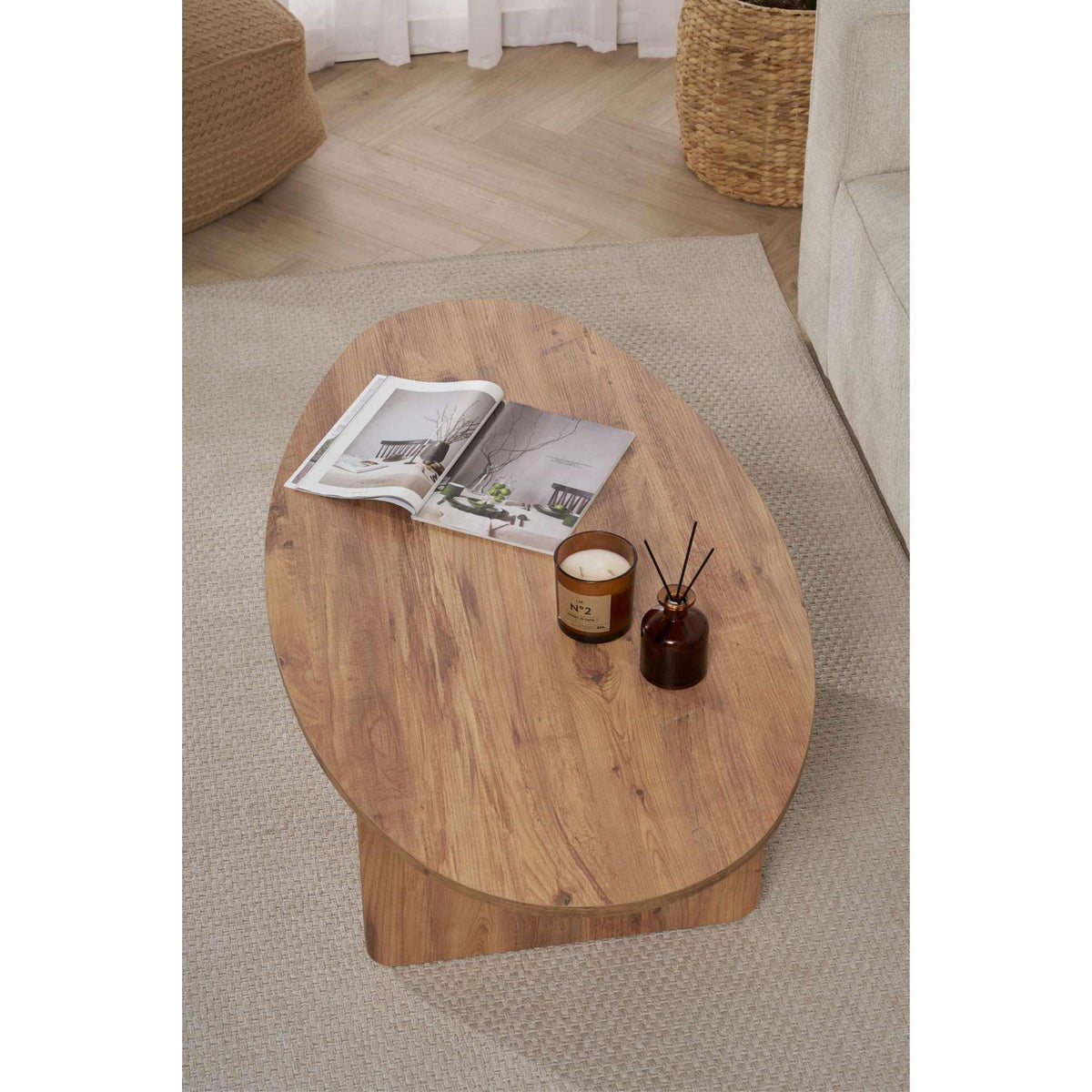 Oval coffee table with warm wood grain finish and curved pedestal-like base.