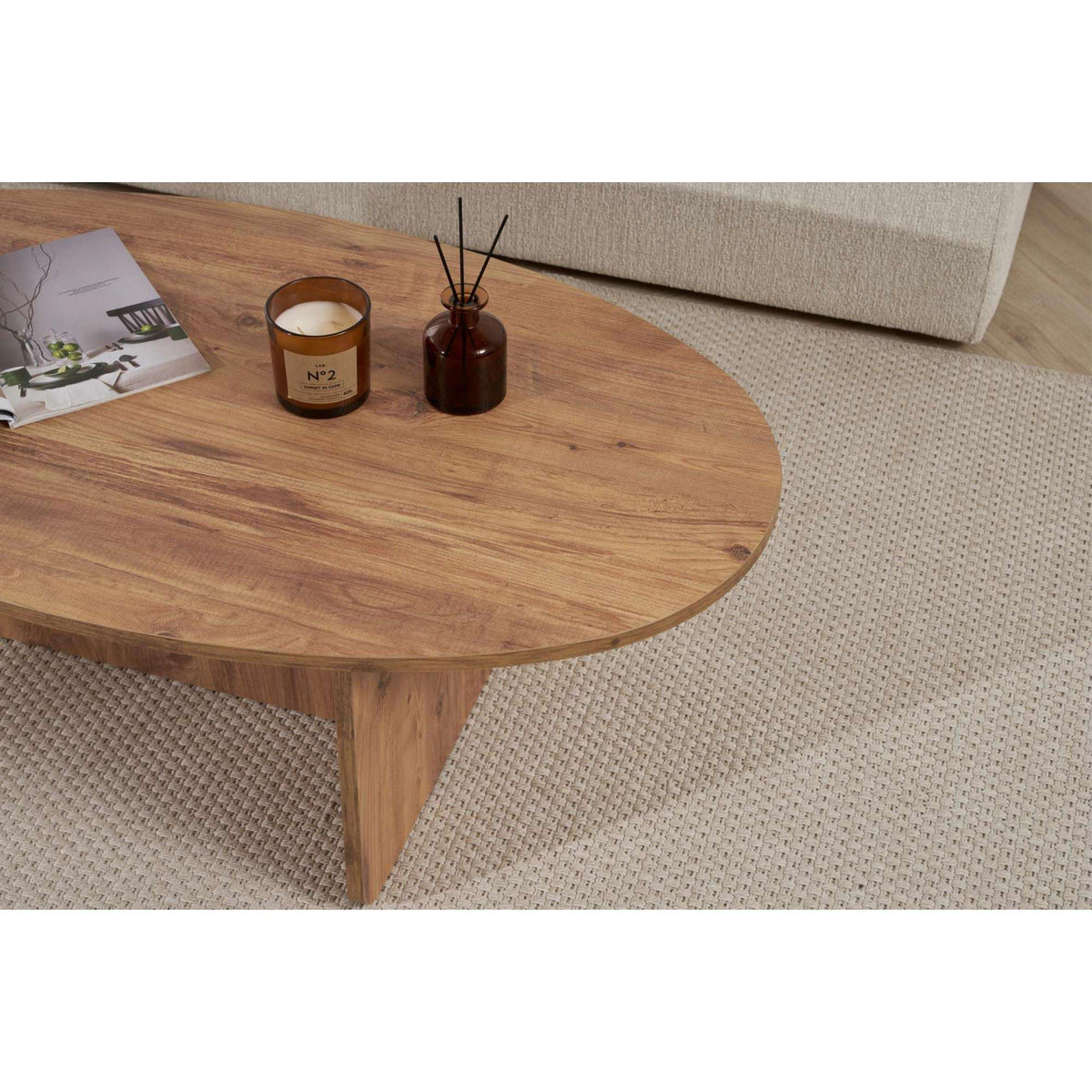 Oval dark wood coffee table with smooth rounded top and two drink candles on it.