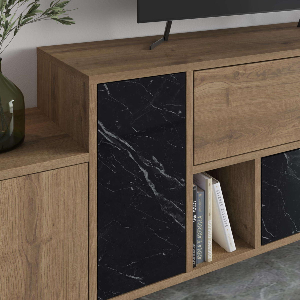 Close-up of wood-look TV stand paneling with black marble-effect door and open book shelf