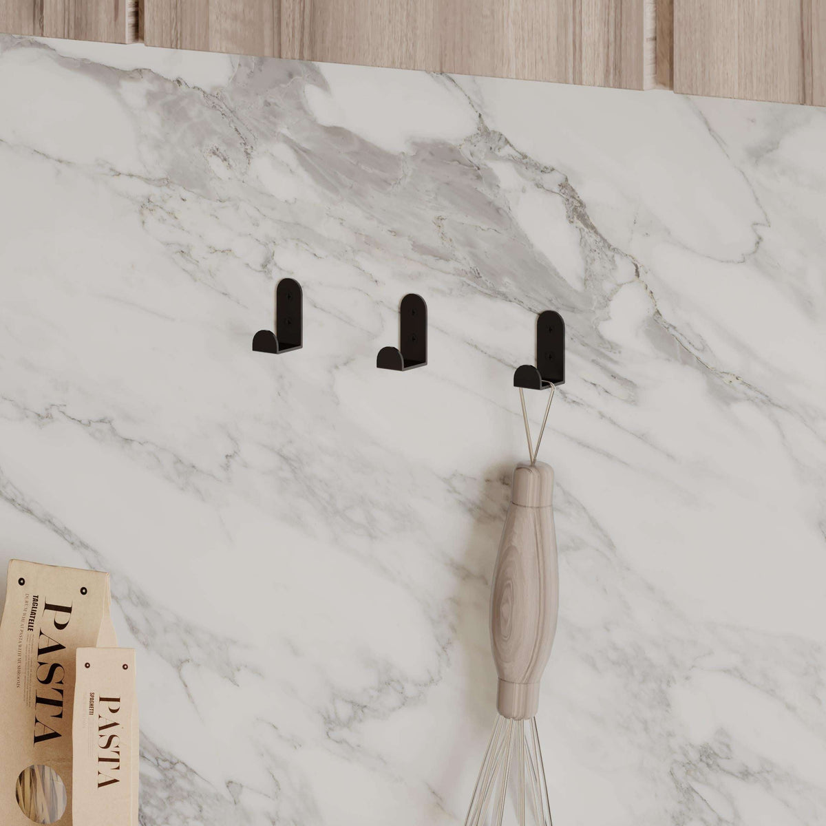 Three black metal wall hooks holding a light wood and beige holder
