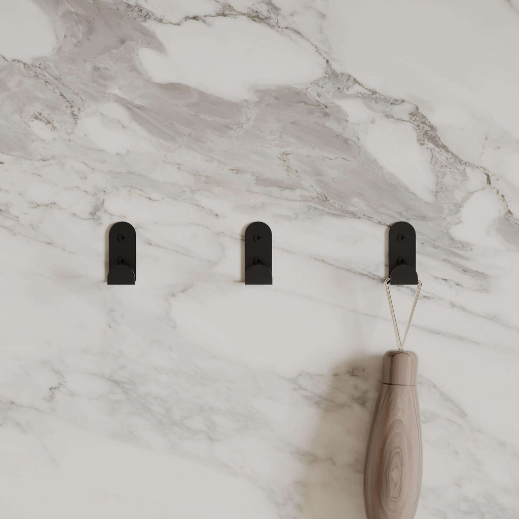 Three black metal wall hooks with a light wood handle and hanging items