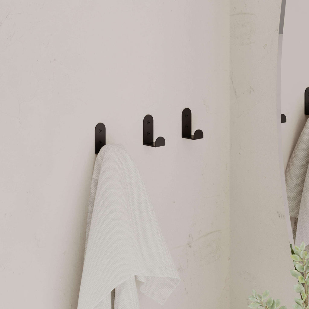Set of 3 black metal wall hooks holding a white towel