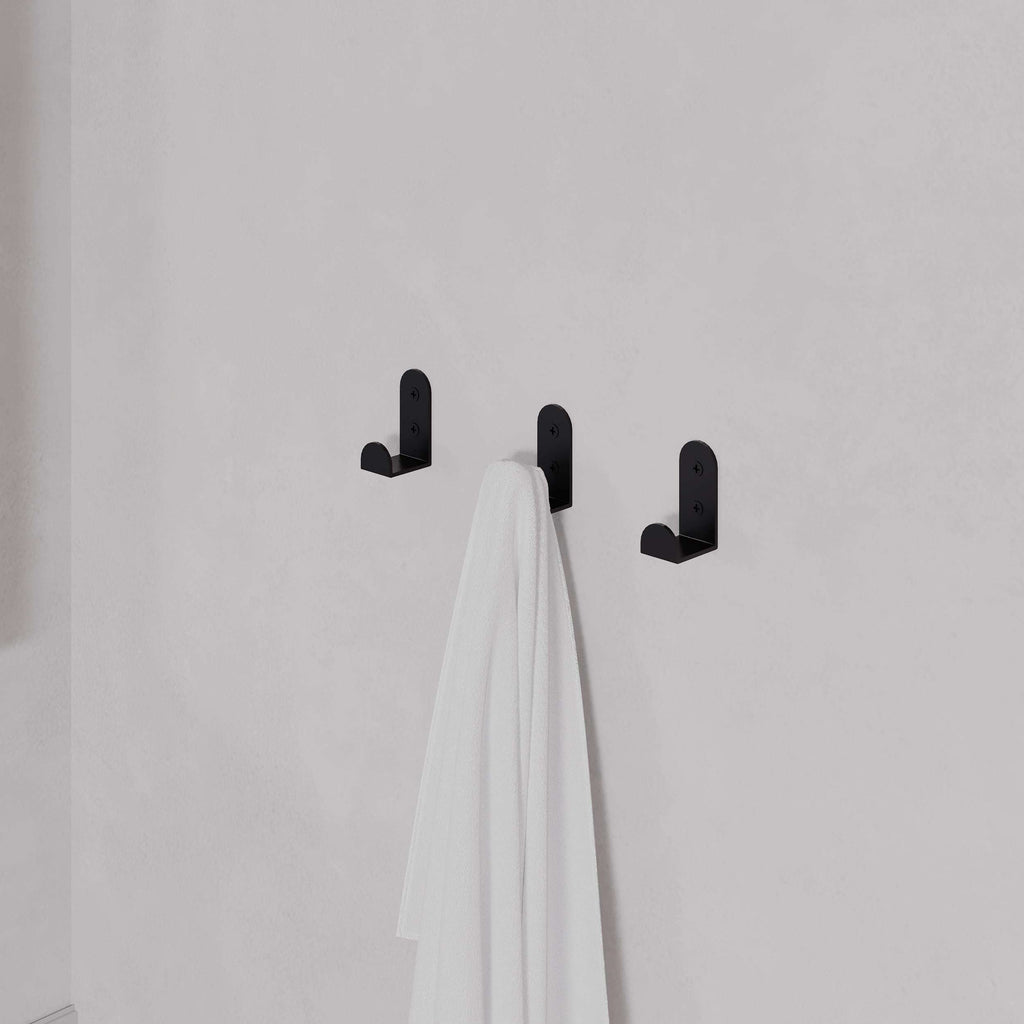 Set of 3 black metal wall coat hooks holding white towels