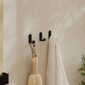 Set of 3 black metal wall coat hooks with curved base and mounting holes