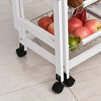 Close-up of white rolling kitchen cart legs and wire baskets filled with onions and produce