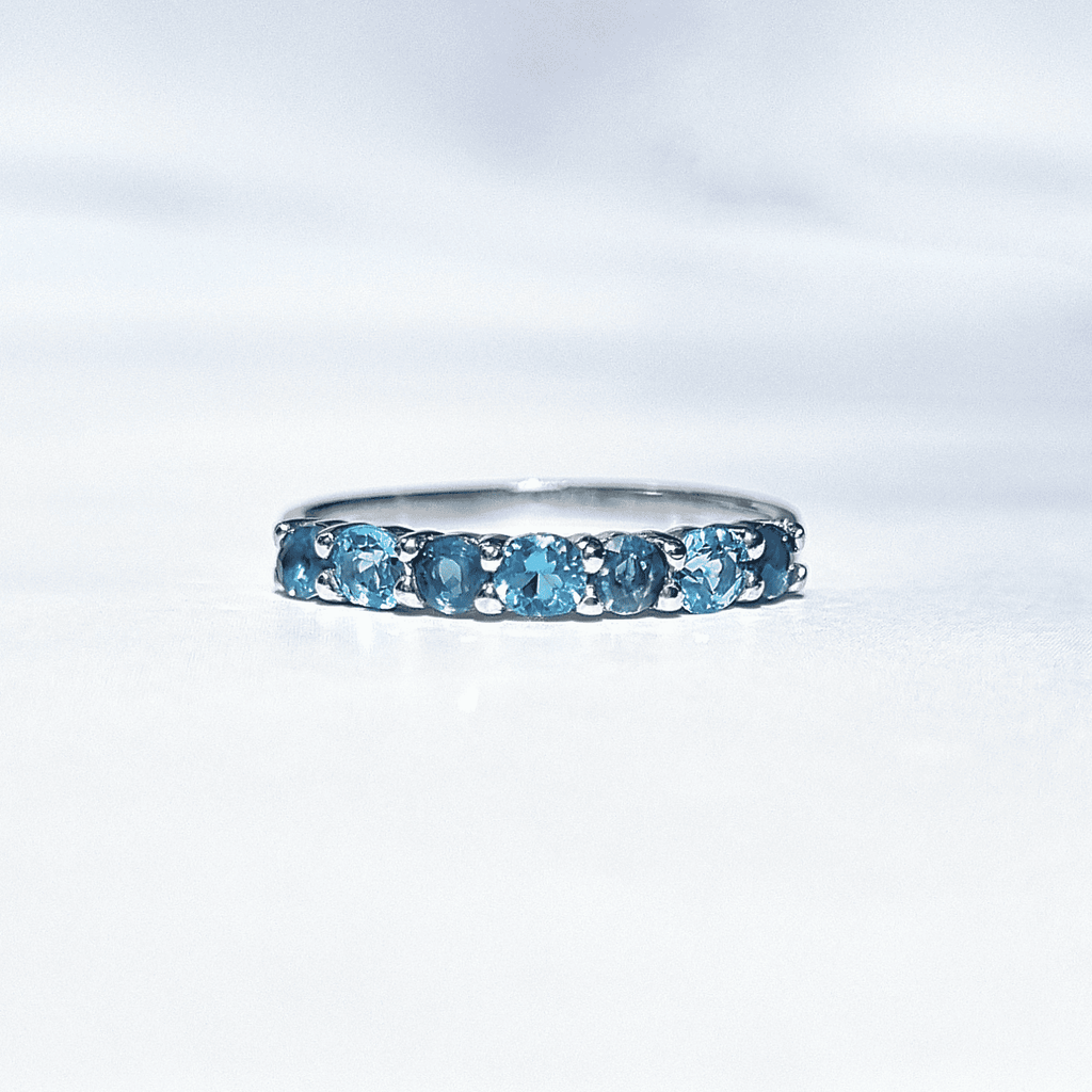 Sterling silver half-eternity band with a row of oval blue gemstones