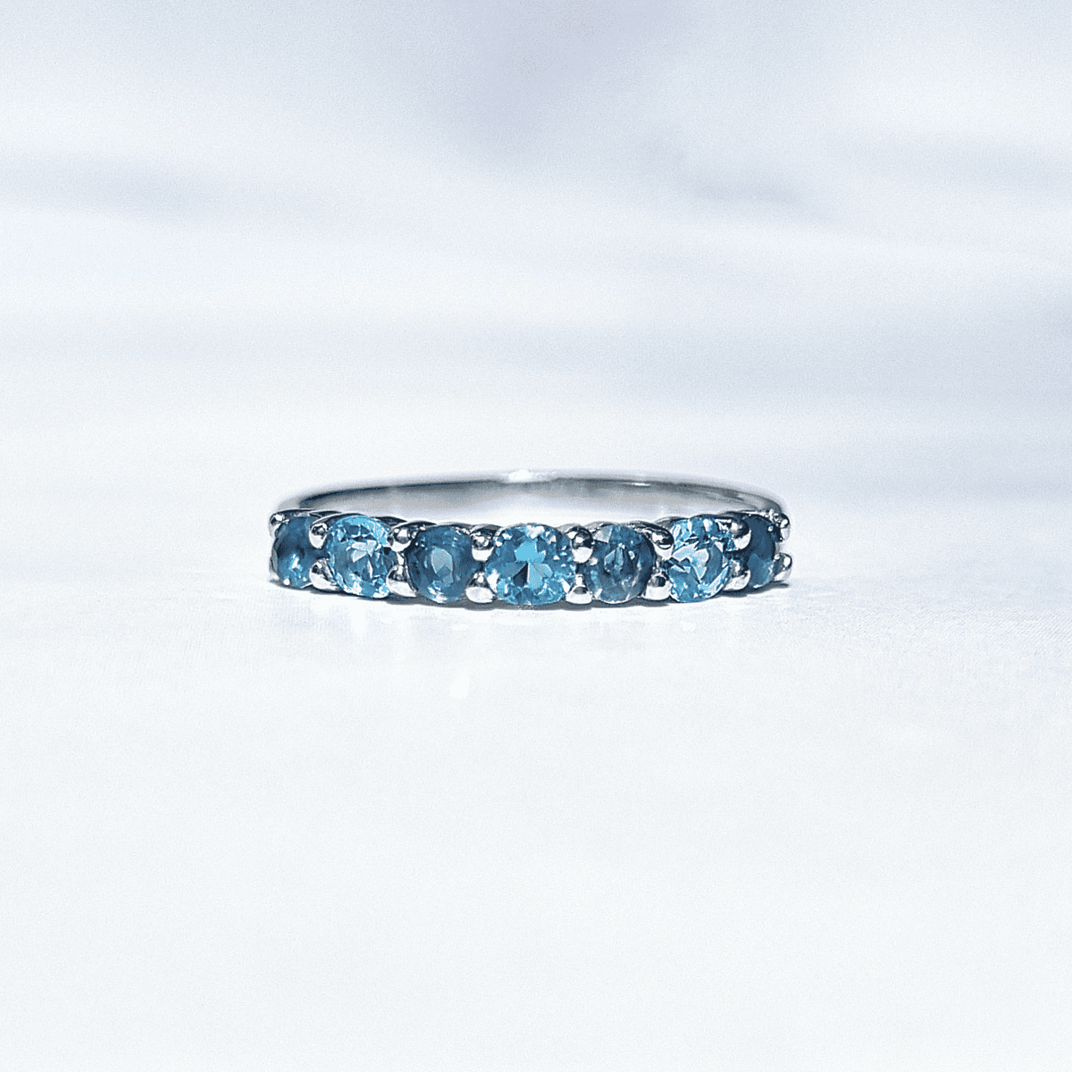 Sterling silver half-eternity band with a row of oval blue gemstones
