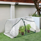 Mini greenhouse with white mesh cover and green frame, plants inside on outdoor lawn