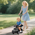 Black ride-on push car walker with child seated and adult pushing by the handle