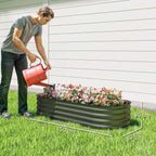 Dark grey raised metal garden bed planter with blooming flowers being watered