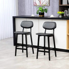 Two black bar stools side by side with cushioned seat and footrest between wooden legs