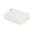 White cot bed waterproof mattress protector, folded blanket-style with stitched edges.