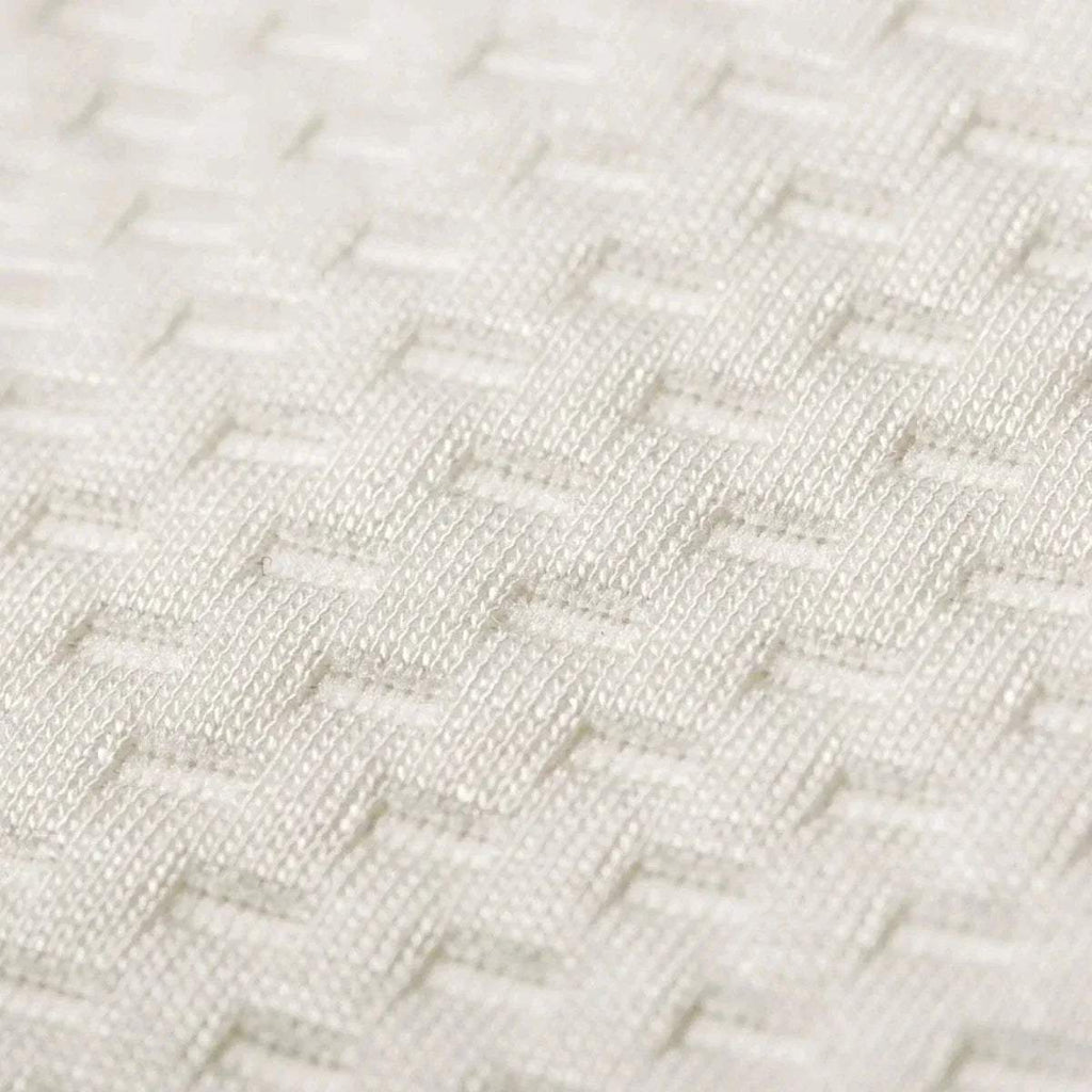 Close-up of white quilted waterproof mattress protector fabric with raised pattern.