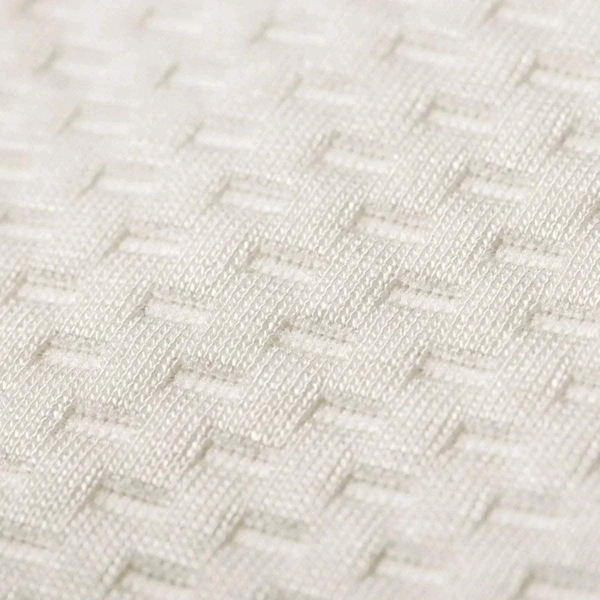 Close-up of white quilted waterproof mattress protector fabric with raised pattern.
