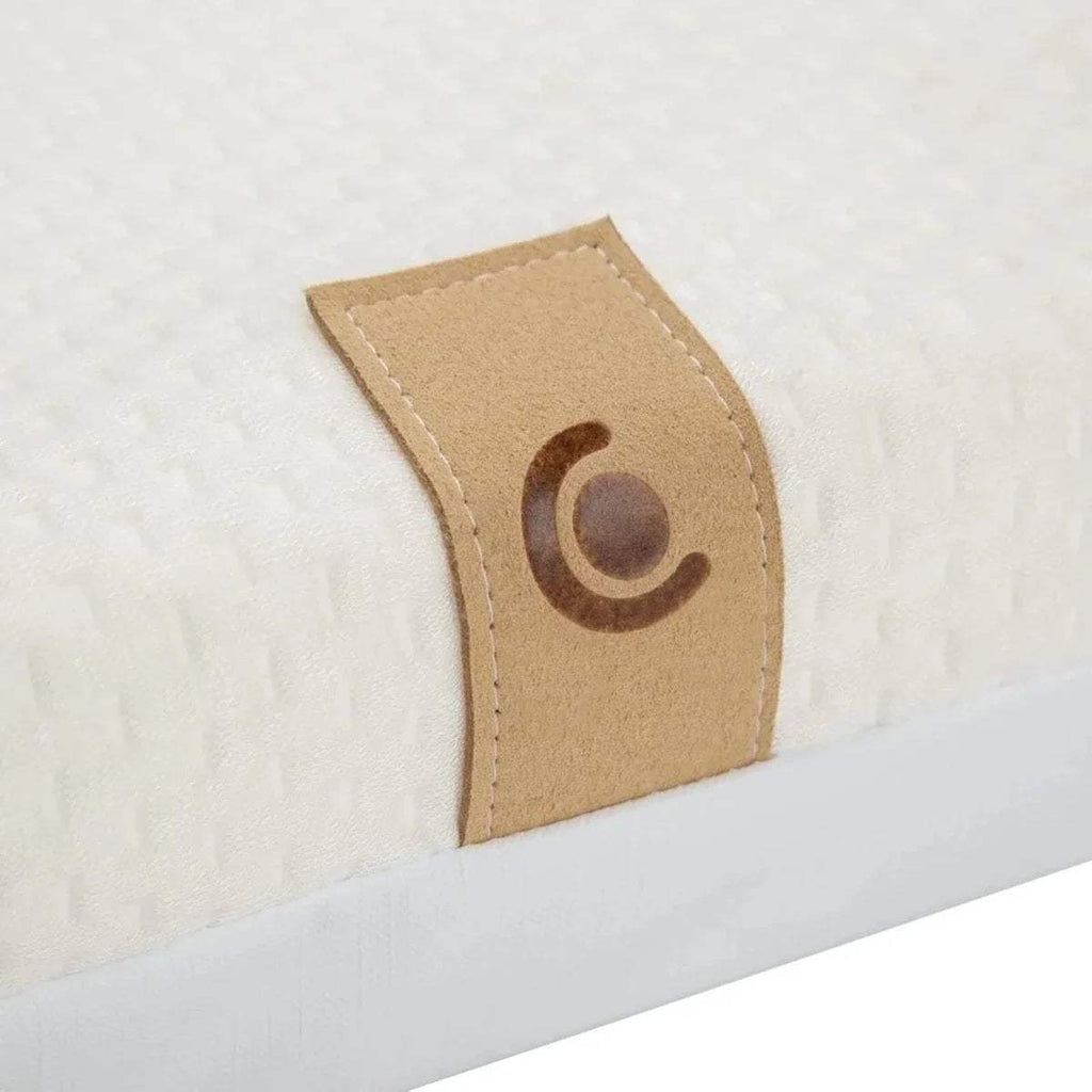 Close-up of white cot mattress cover patch with brand-style tan fabric label