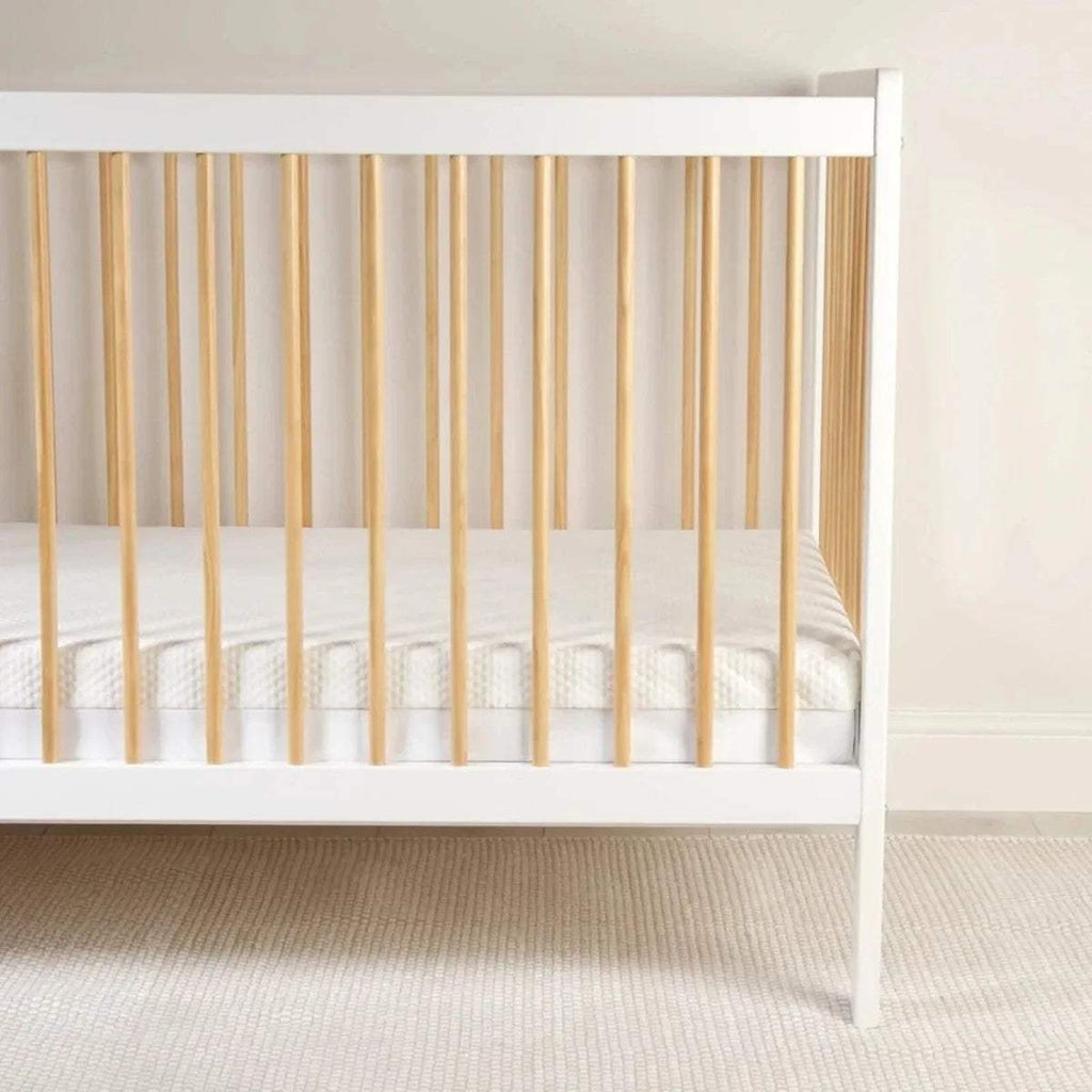 Baby cot with white mattress fitted on slatted base