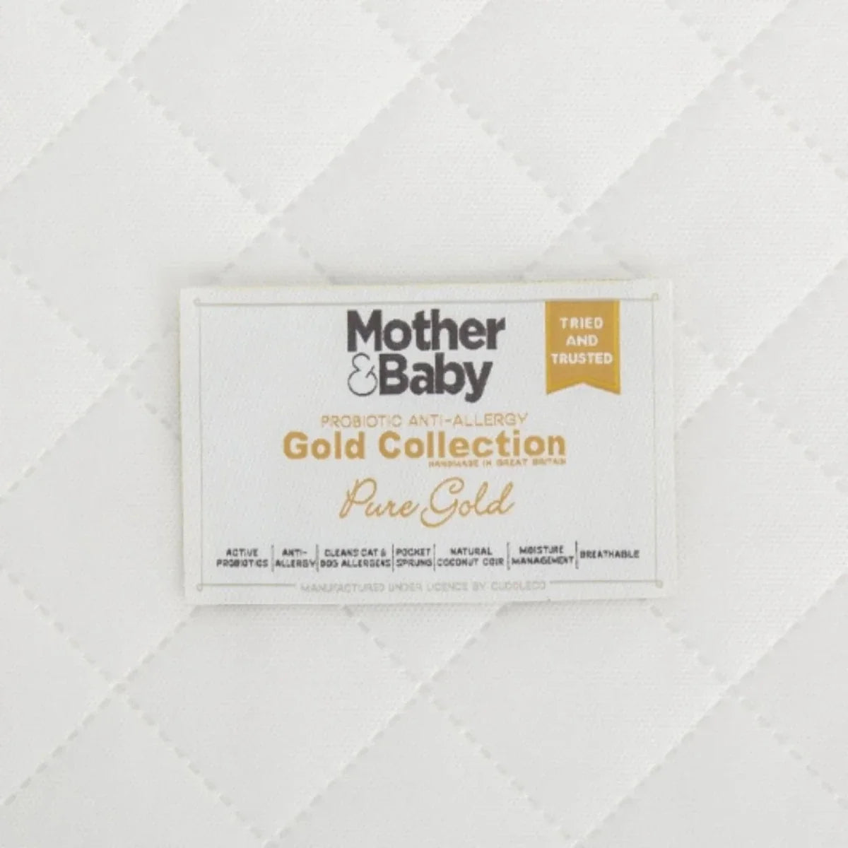 White cot mattress close-up of gold collection label on quilted cover