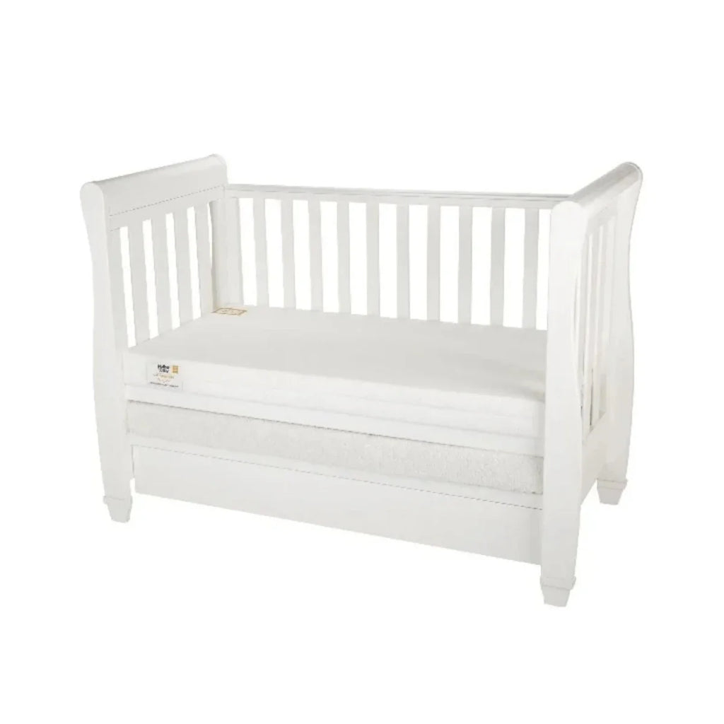 White cot mattress placed in a white wooden cot frame, quilted cover
