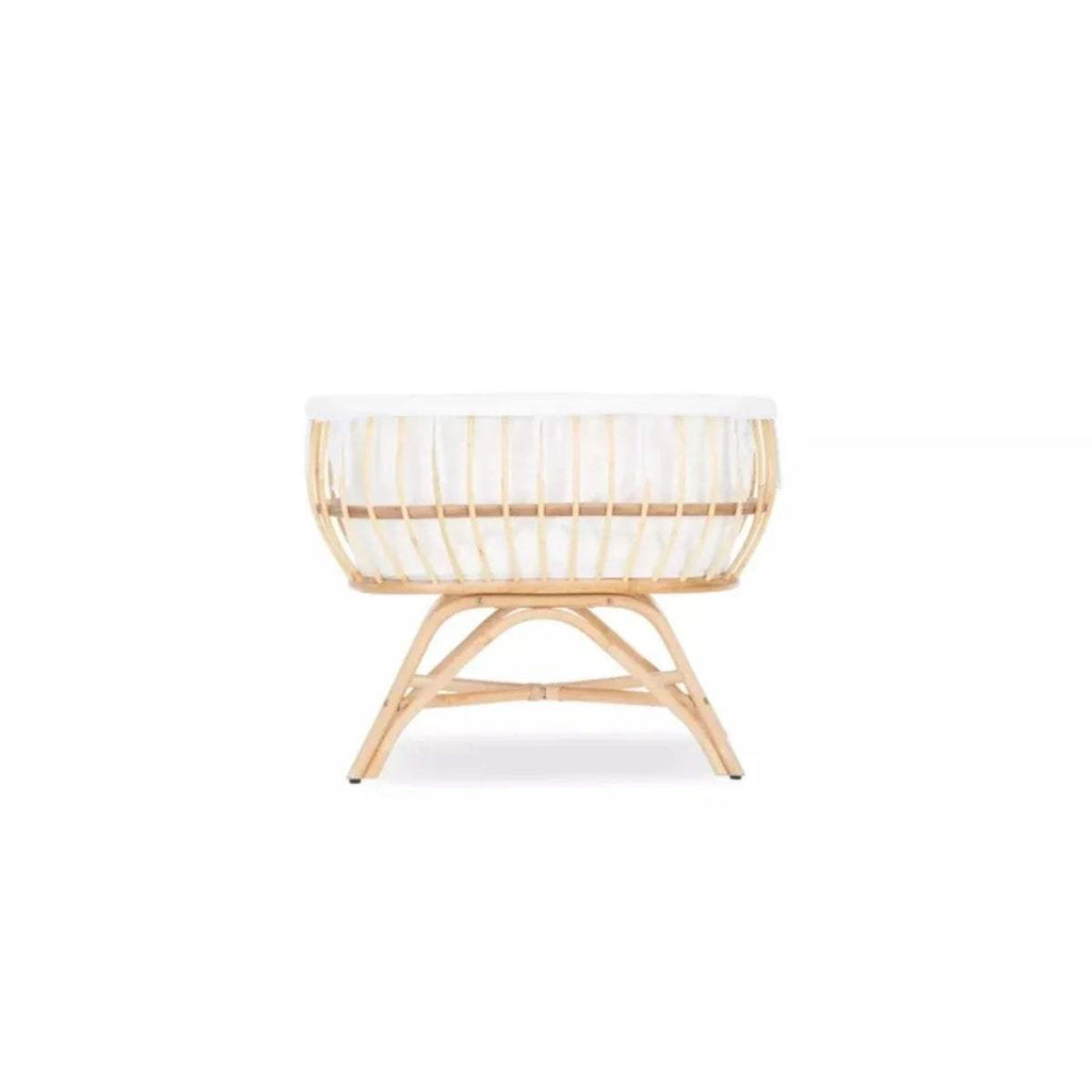 Natural rattan baby crib with white fabric bedding and cross-legged base