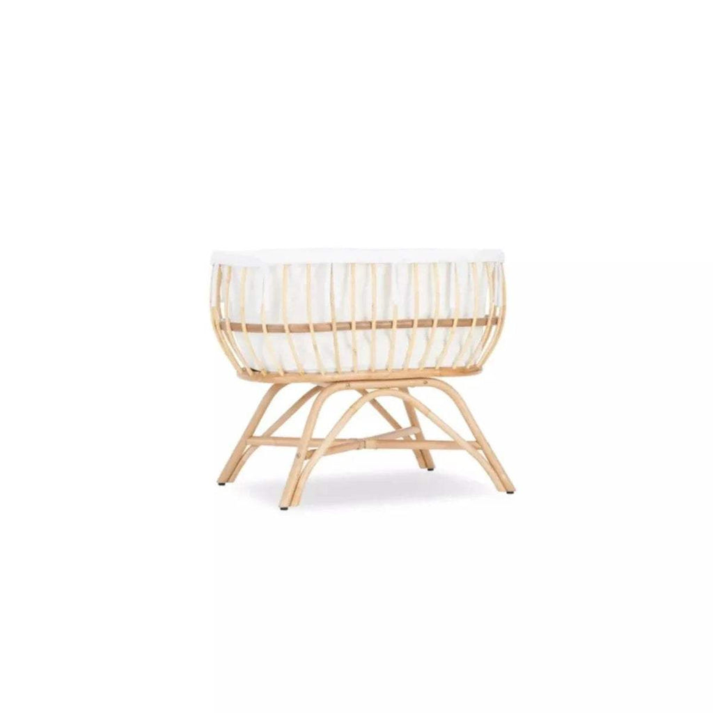 Natural rattan baby crib with white padded rim and woven basket base