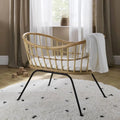 Rattan wave crib with white blanket, curved headboard, black metal stand legs