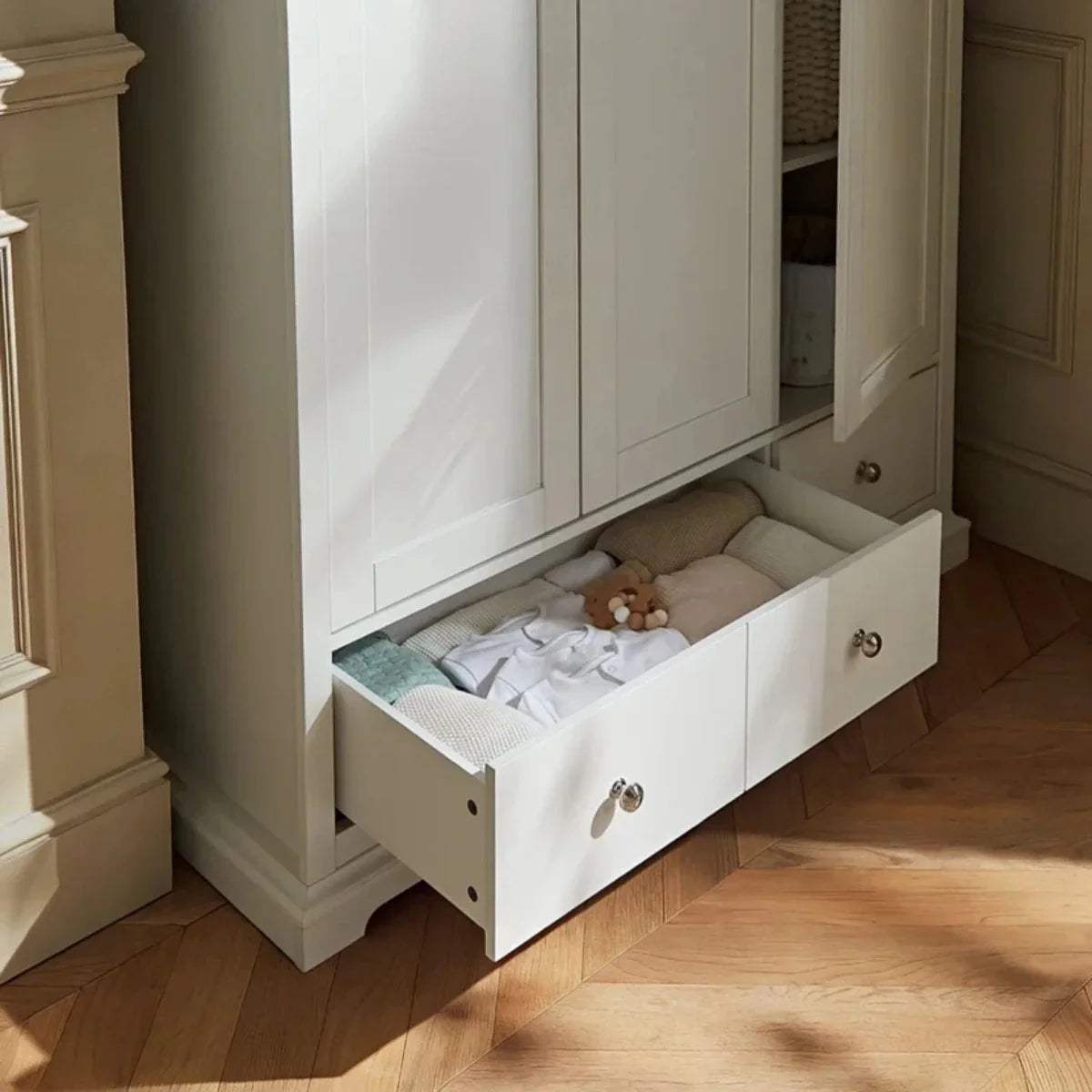 White wardrobe base drawer open, showing folded bedding inside