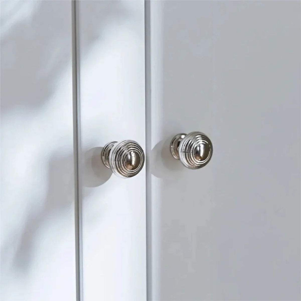 Chrome round knobs on a white wardrobe door panel