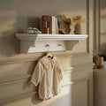White wall shelf with scalloped apron edge and underside peg details