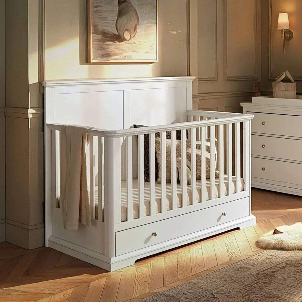 White cot bed with slatted sides and under-drawer front panel