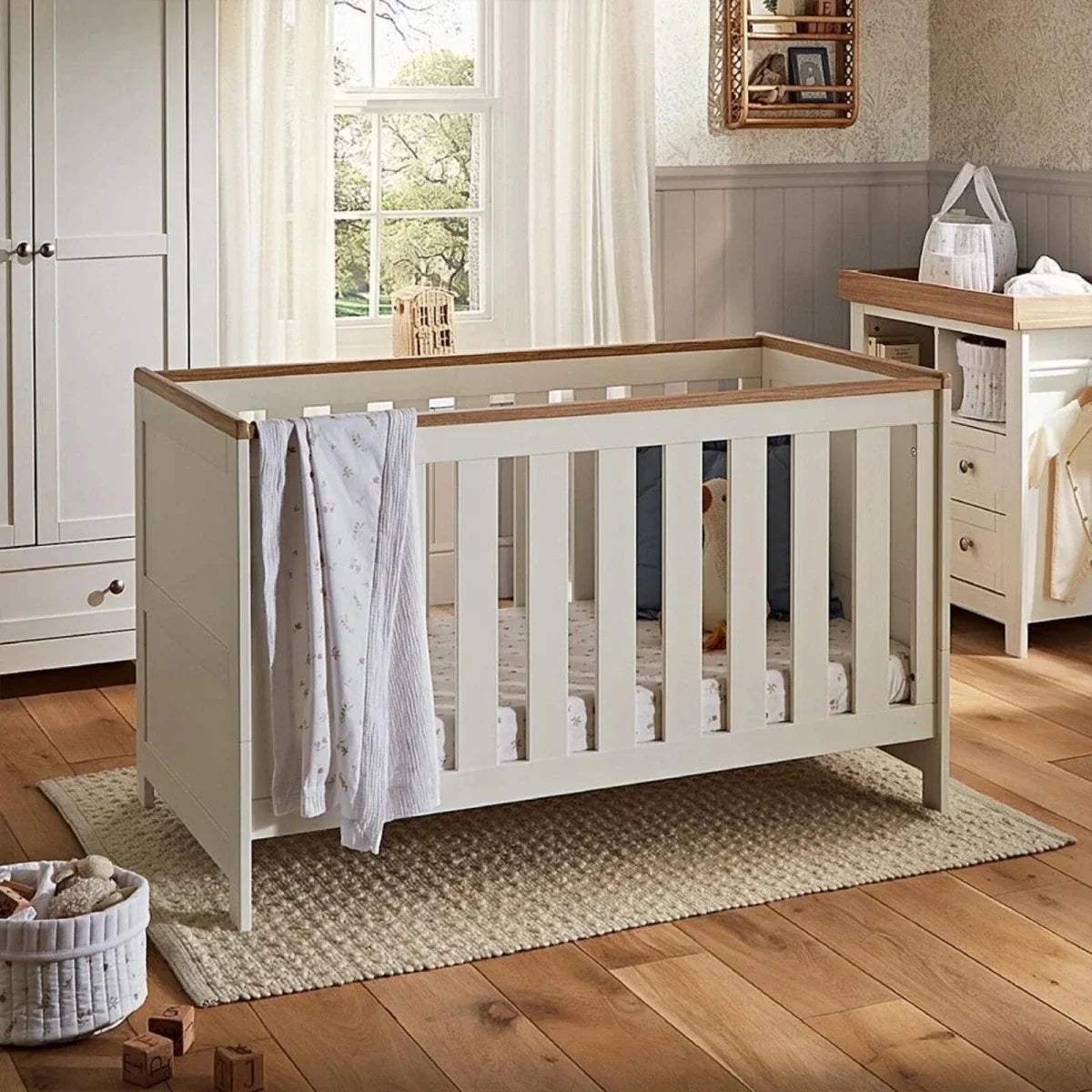 White cot bed with slatted sides and light oak top rail, open front