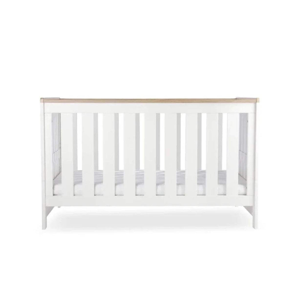 White cot bed front view with vertical slats and oak-toned top rail