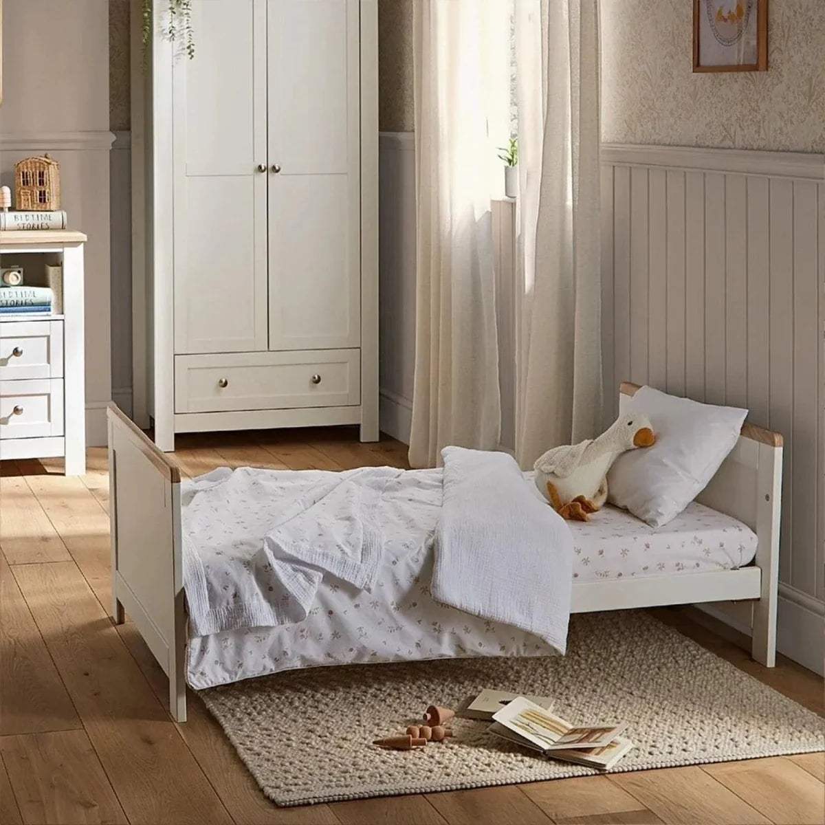 White low cot bed with slatted side rail and white padded mattress