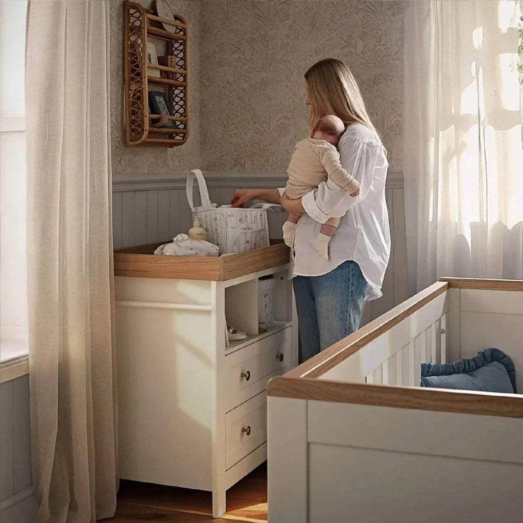 White baby changing dresser with oak top and open shelf storage